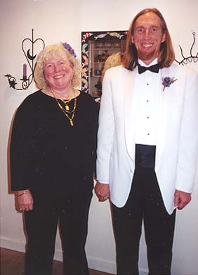 Deborah in her black outfit and Jim in his white tux with matching floral hair piece and boutonier.