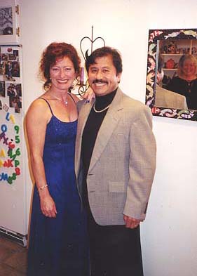 Cheri in her blue/purple luminous gown and George in his black turtleneck with silver chain.